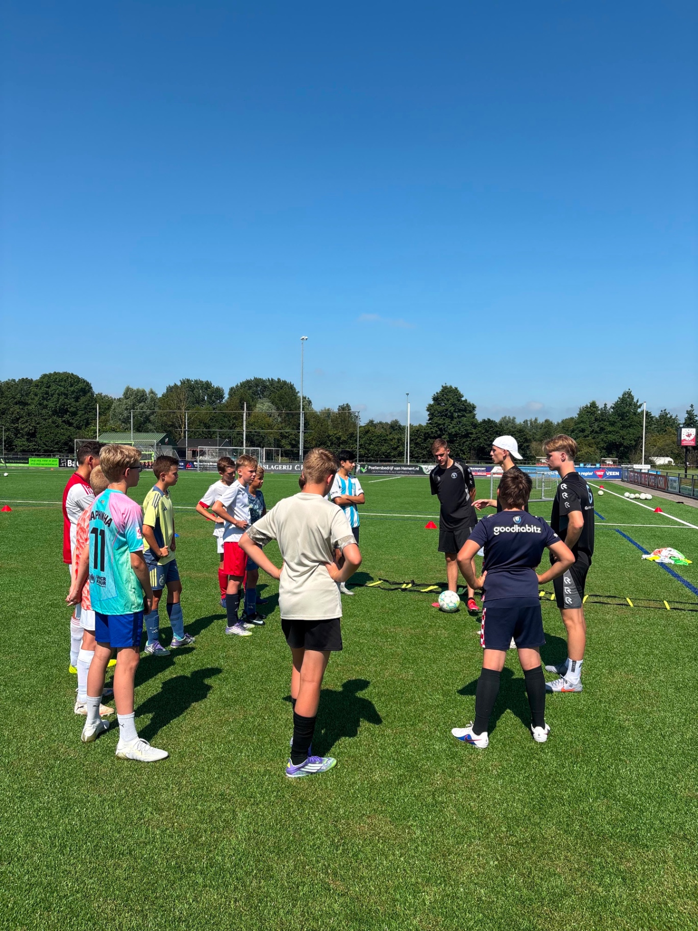 Trainer geeft uitleg aan groep jeugdspelers
